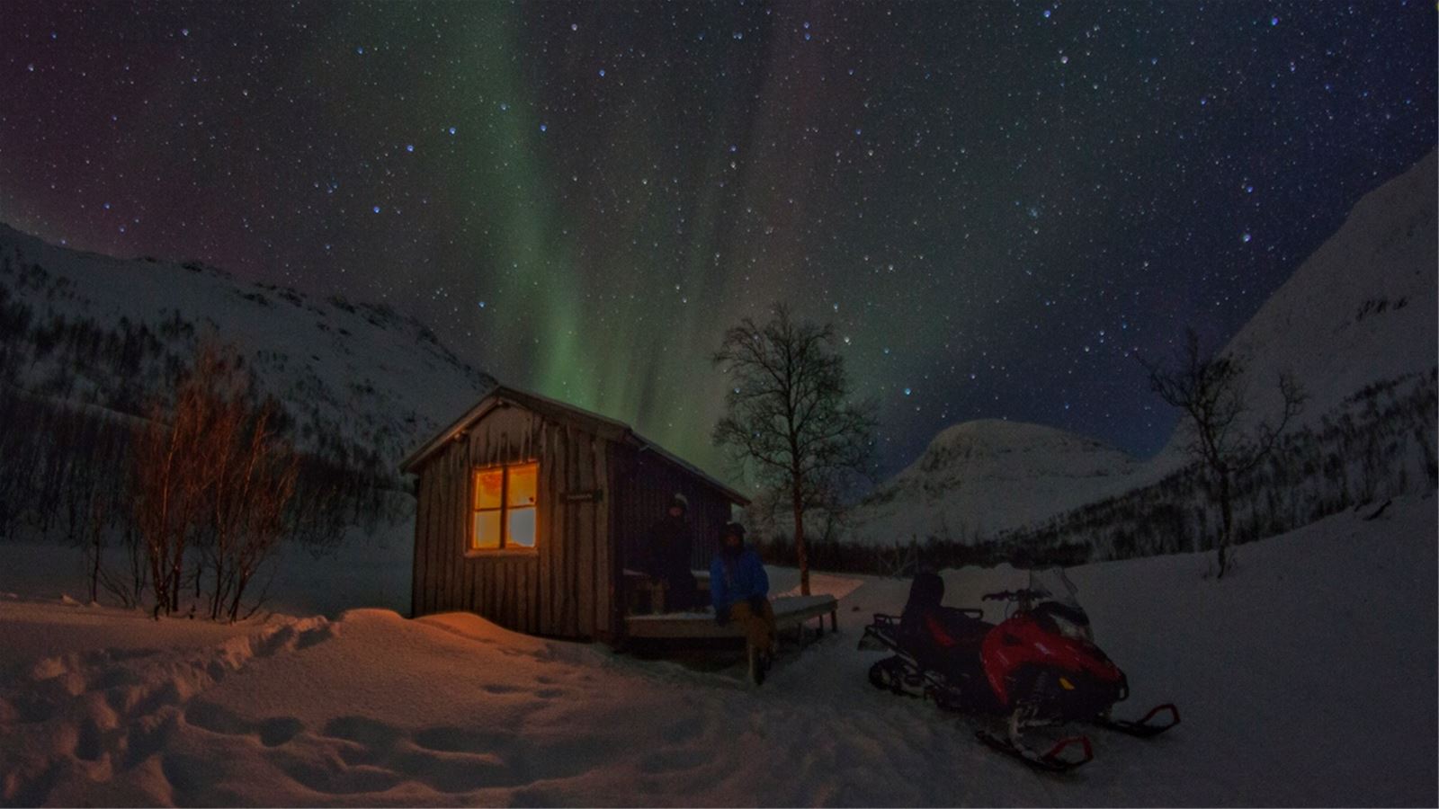 Cabin and snowmobile beneath the aurora