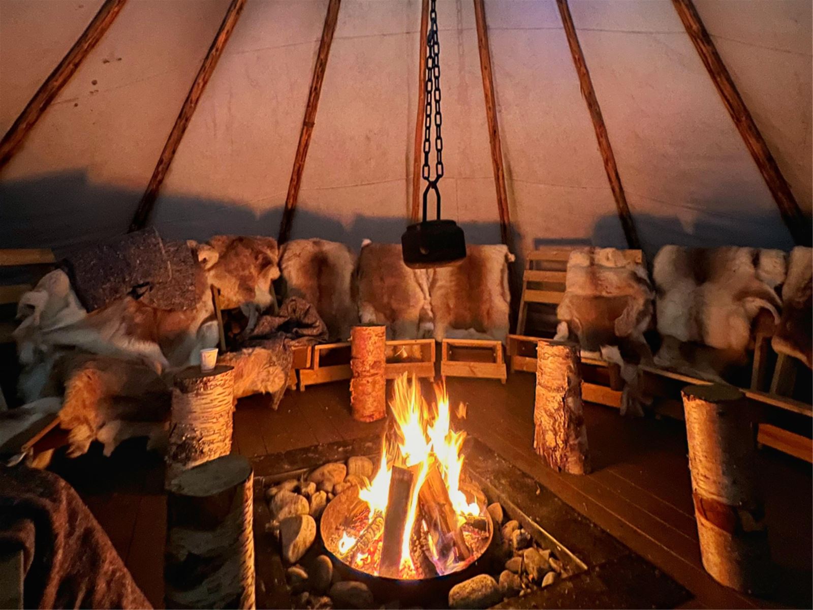 Inside the lavvu with an open fire and reindeer skins