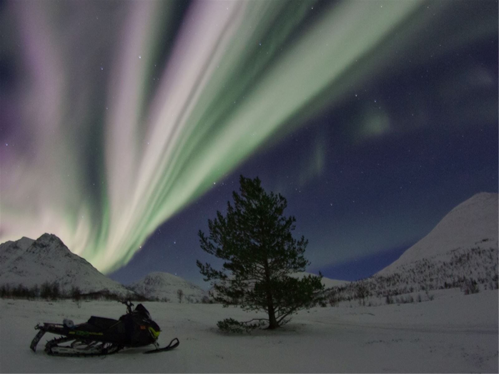 Snowmobile beneath the northern lights
