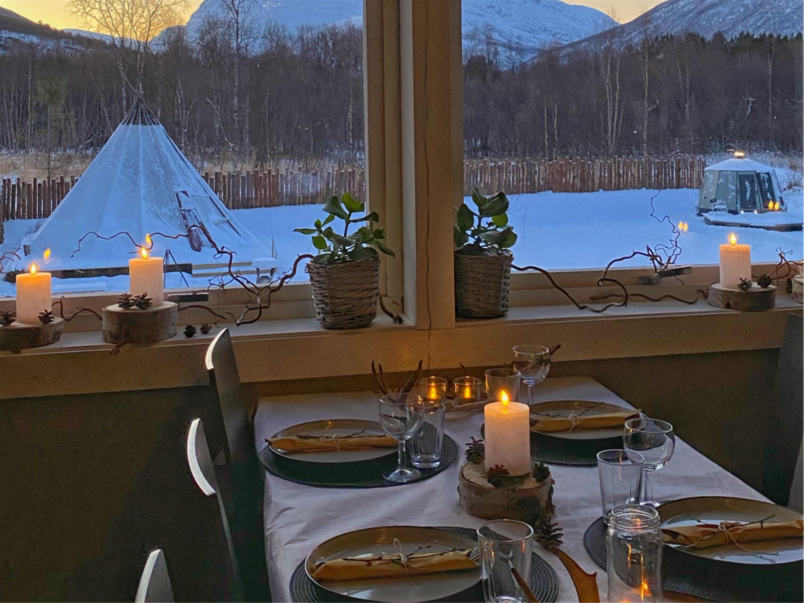 Candlelit table overlooking the lavvu and an AuroraHut
